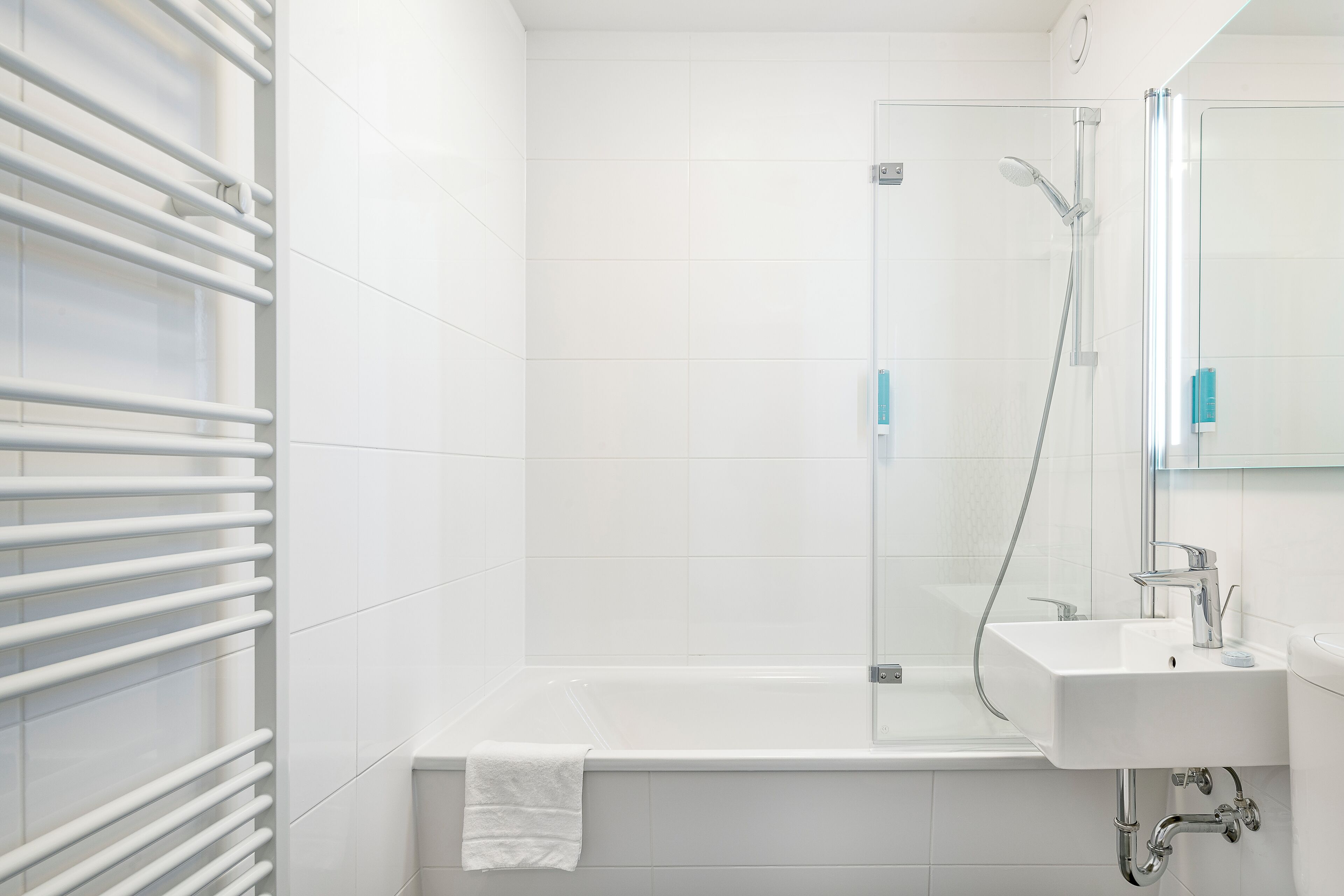 Et moderne badeværelse med badekar, bruser og håndvask.