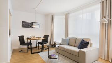 Una sala de estar moderna con un sofá, dos sillones, una mesita y una lámpara.