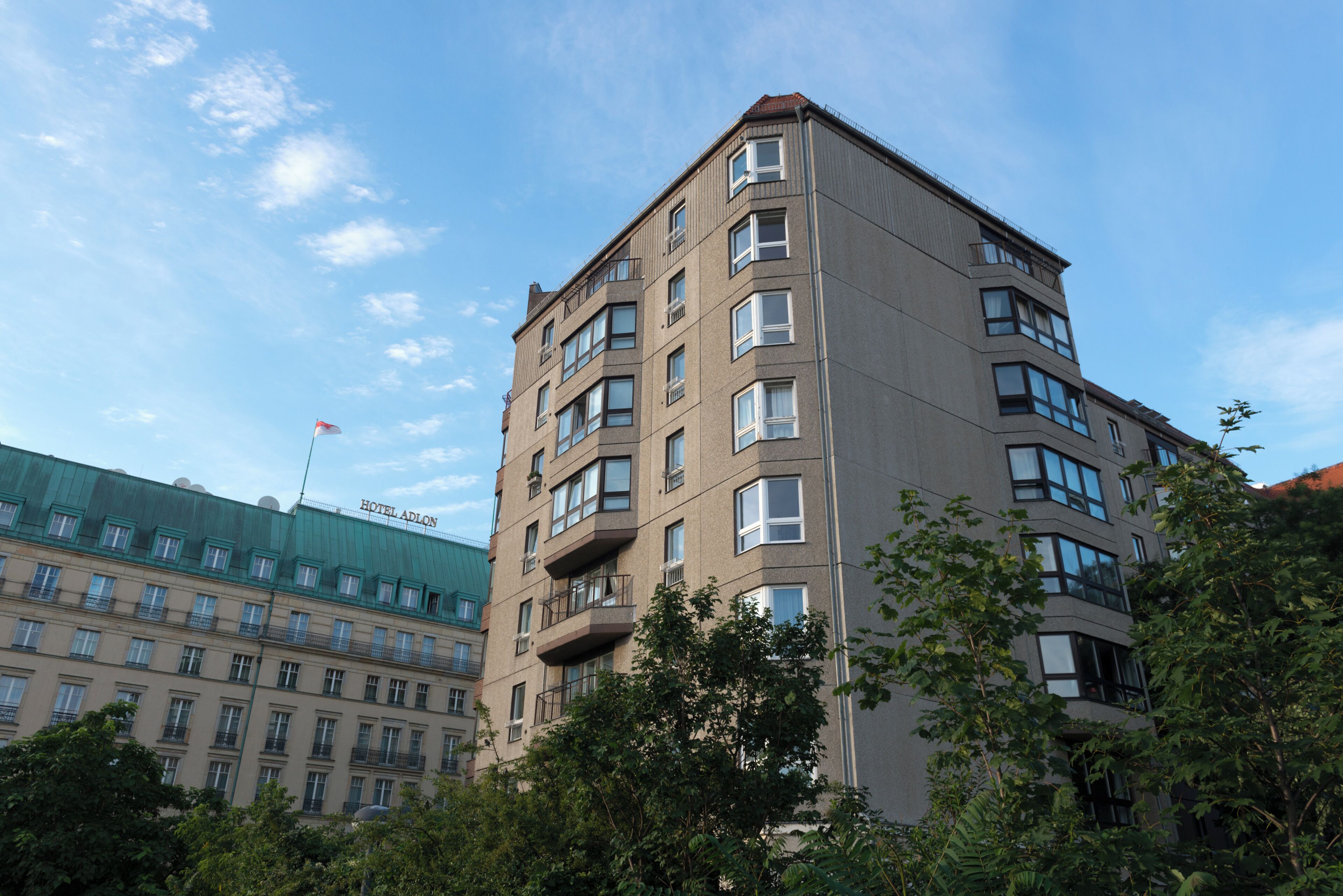 A multi-story hotel with balconies, a green roof, and a clear sky.