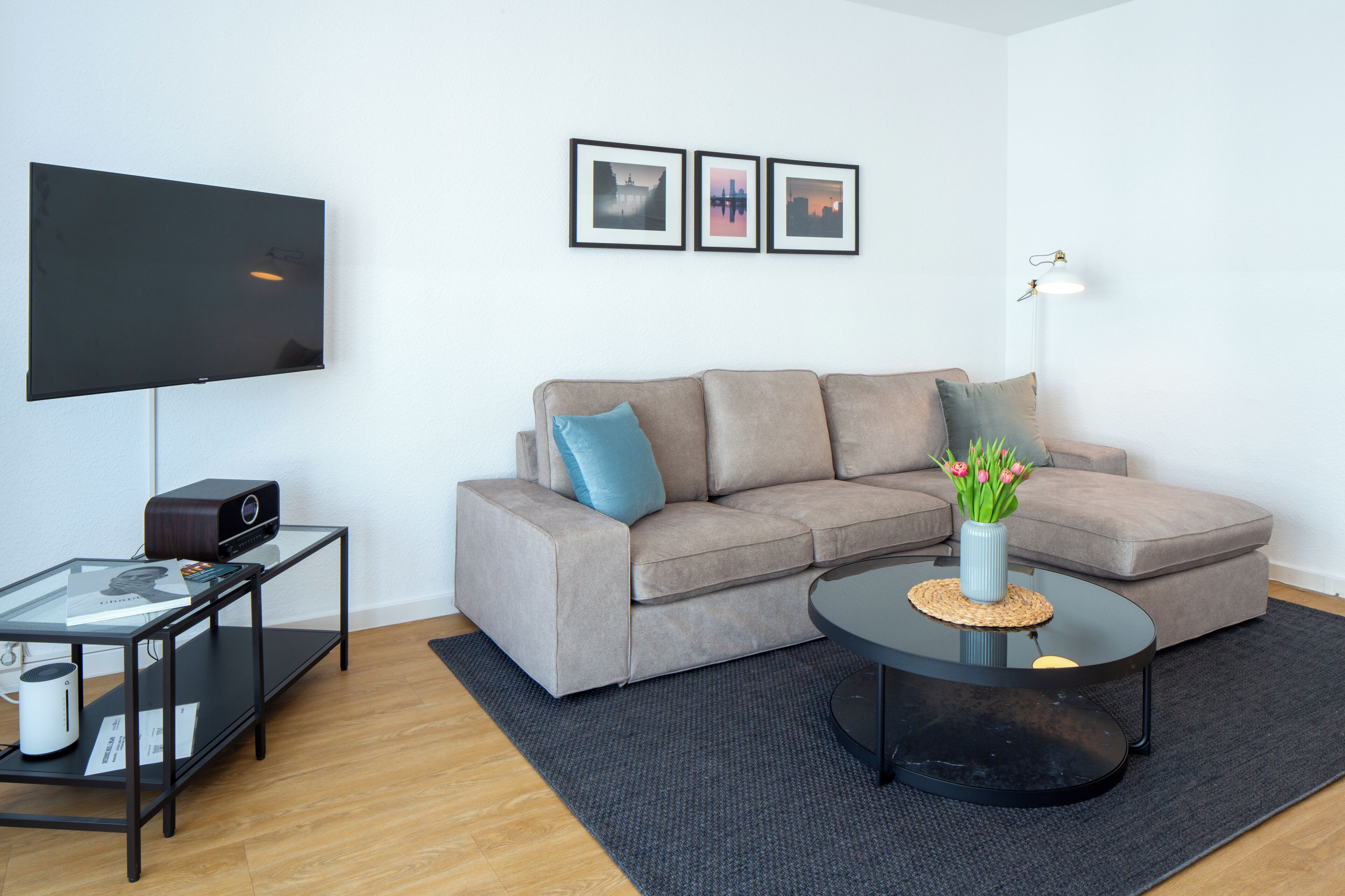 A living room with a flat-screen TV, a sofa, a coffee table, and a lamp.