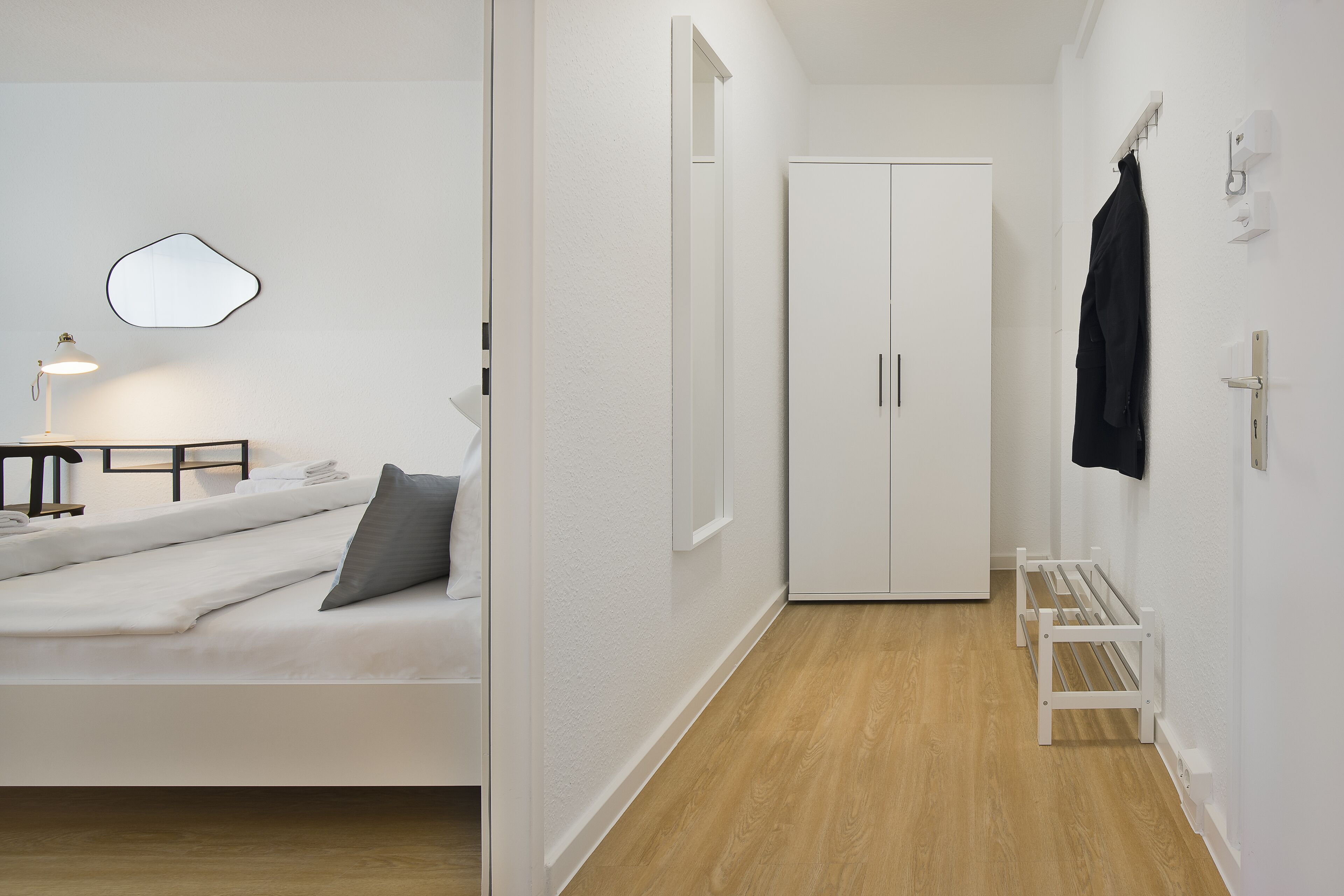 A modern bedroom with a bed, bedside table, lamp, and a wardrobe.