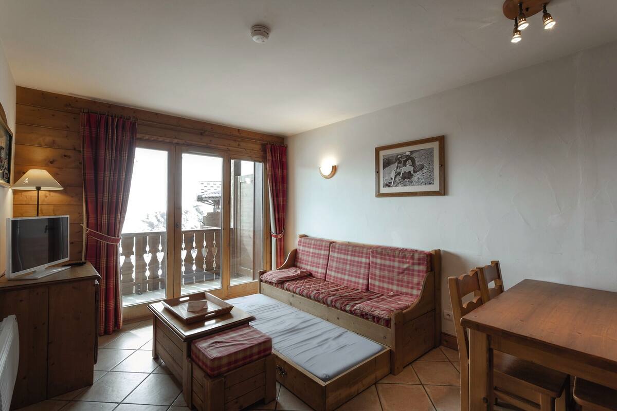 A cozy room with a wooden bed, a dining table, and a TV.