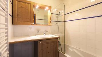 A bathroom with a wooden vanity, a sink, a mirror, and a glass-enclosed shower.