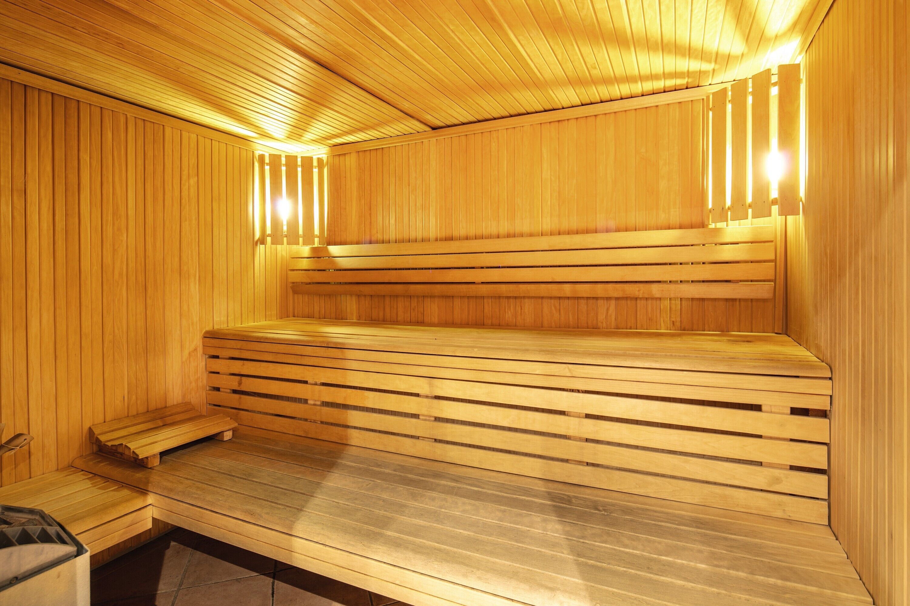 Un sauna avec des bancs en bois, un banc situé à l’extrémité et un autre à l’autre extrémité.