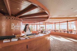 A reception desk with a sign reading 'Belamendi clubs' and a woman seated behind it. - Belambra Clubs Les Menuires - Neige Et Ciel (Les Belleville)