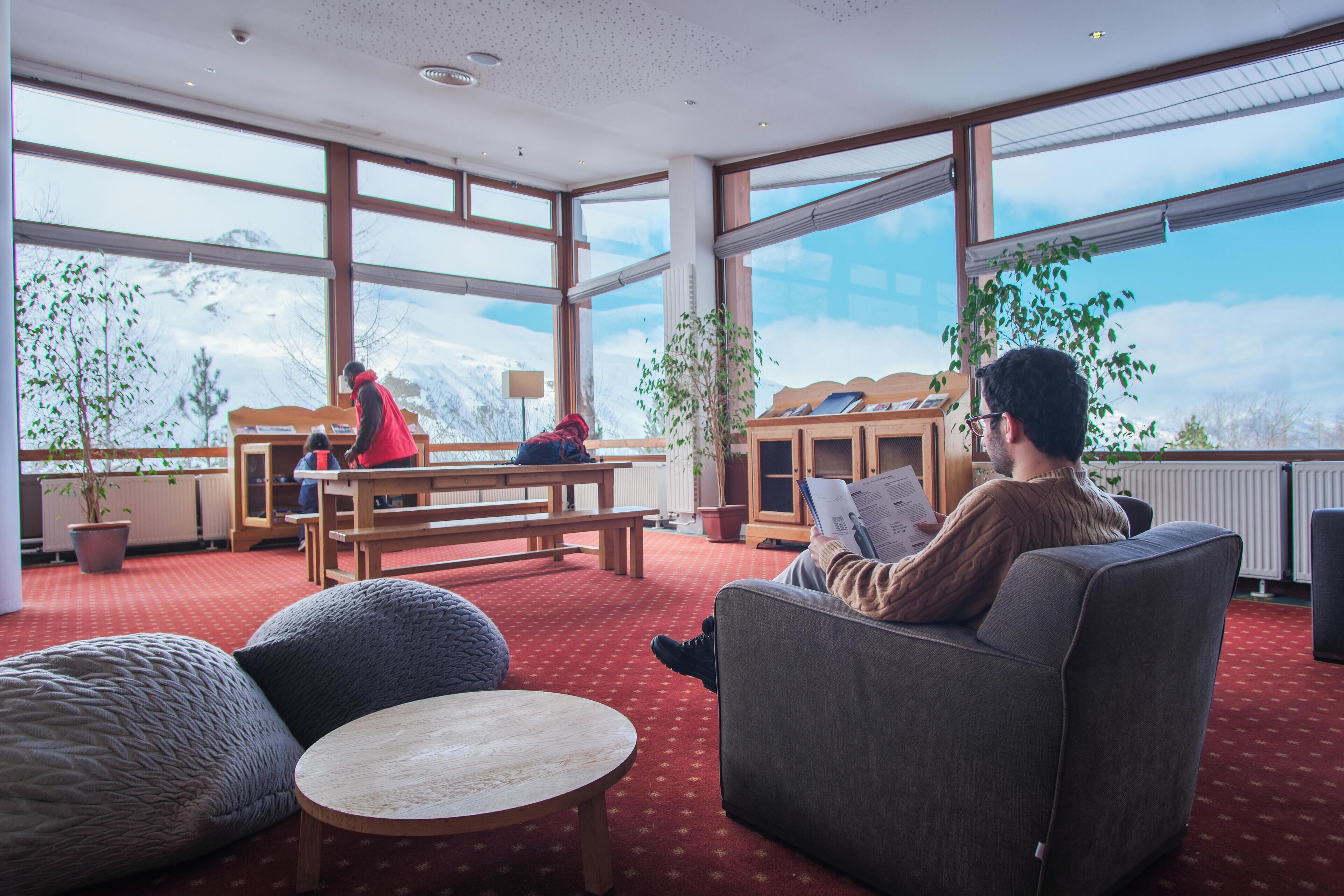 A spacious room with large windows, a wooden table, and comfortable seating.