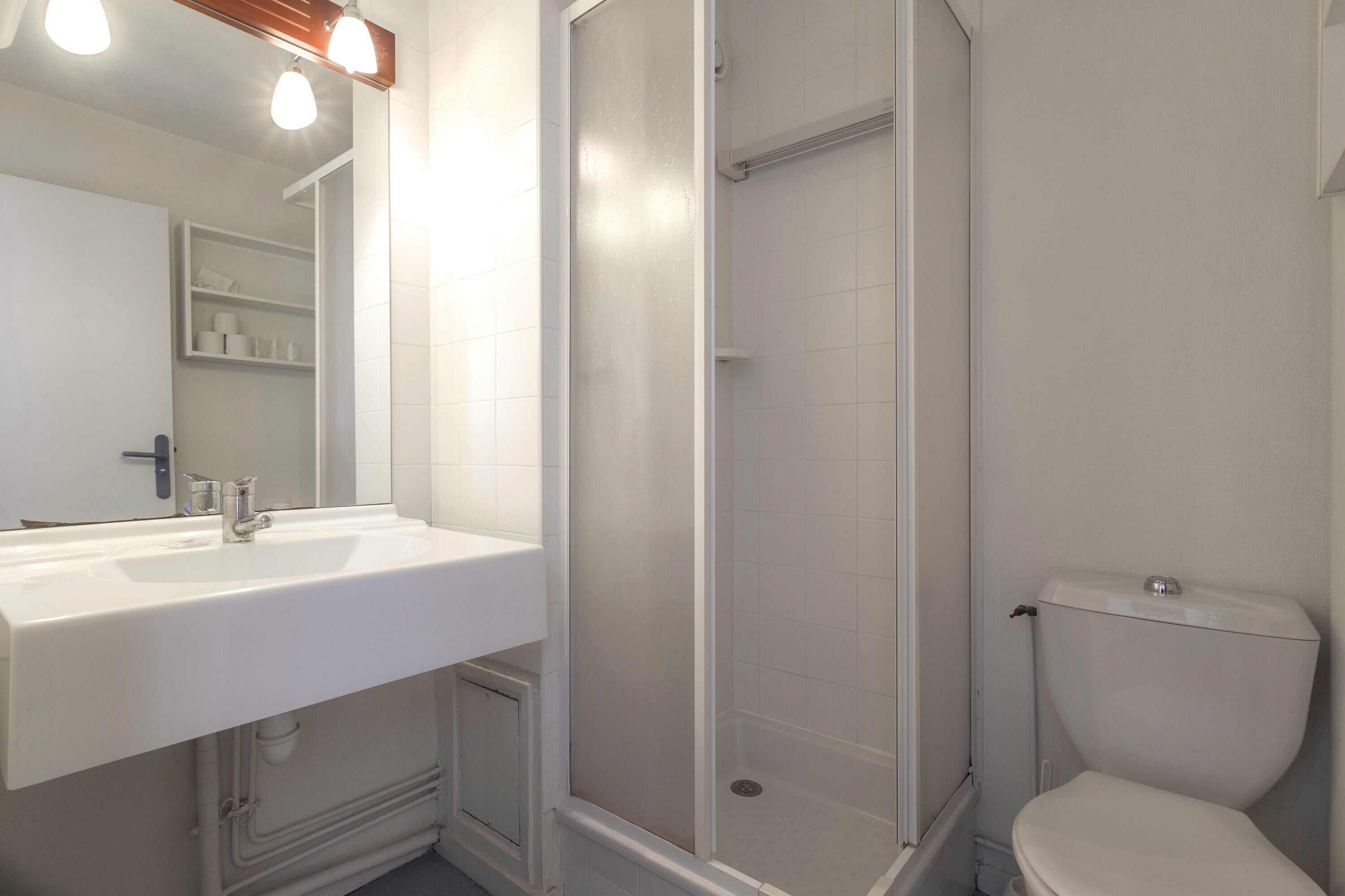 Un baño con lavamanos, espejo y retrete blanco.