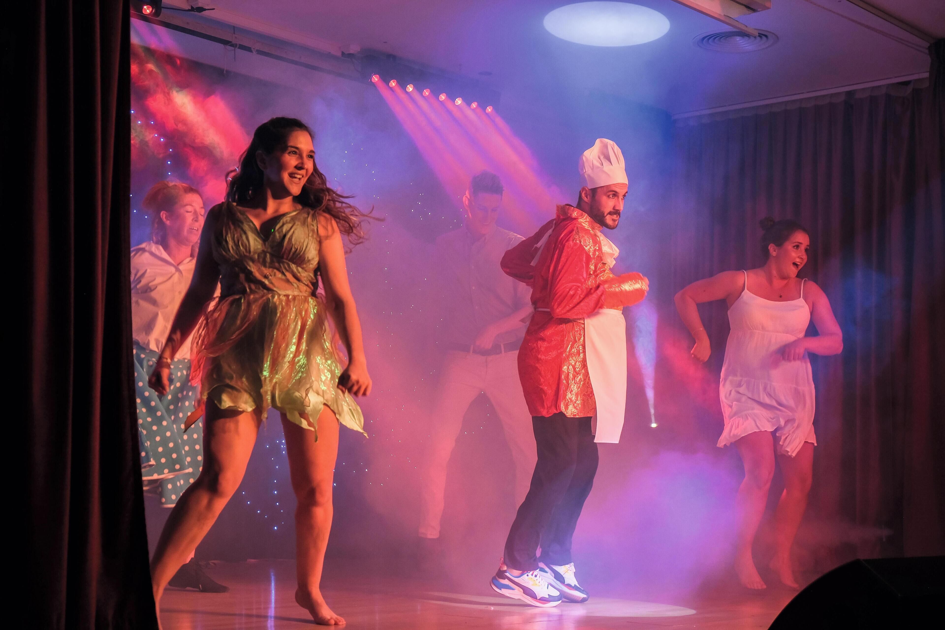 A group of people performing on a stage with a backdrop of lights and smoke.
