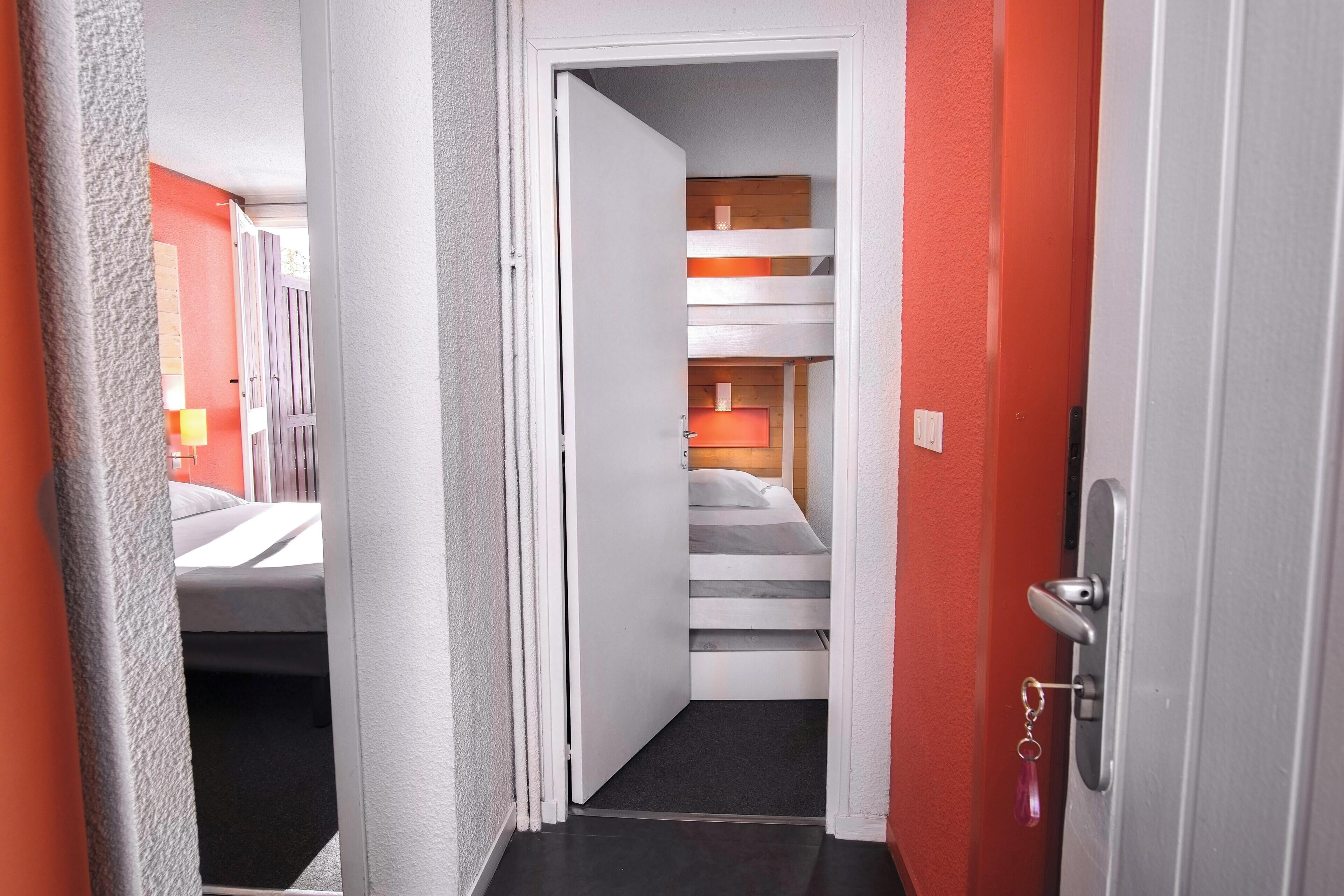 Un couloir d’hôtel avec un escalier menant à une chambre dotée d’un lit et d’une table de chevet.