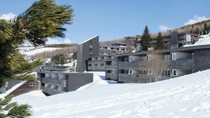 A modern multi-story building with a sloped roof, surrounded by snow-covered ground and trees. - Belambra Clubs Superbesse - Le Chambourguet (Besse-et-Saint-Anastaise)