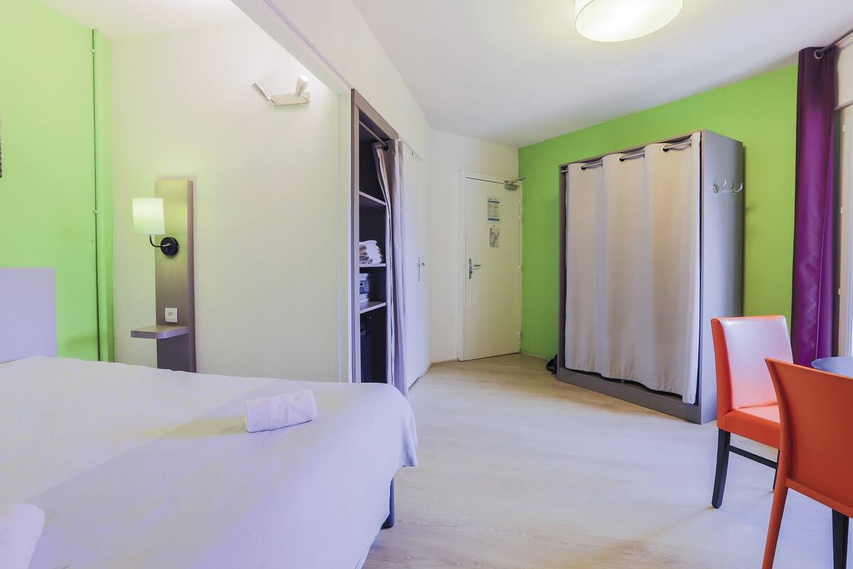 Une chambre d’hôtel comprenant un lit, une chaise, une armoire et un espace douche.