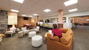 A spacious lobby with a bar area, seating arrangements, and a stone wall. - Belambra Clubs Superbesse - Le Chambourguet (Besse-et-Saint-Anastaise)