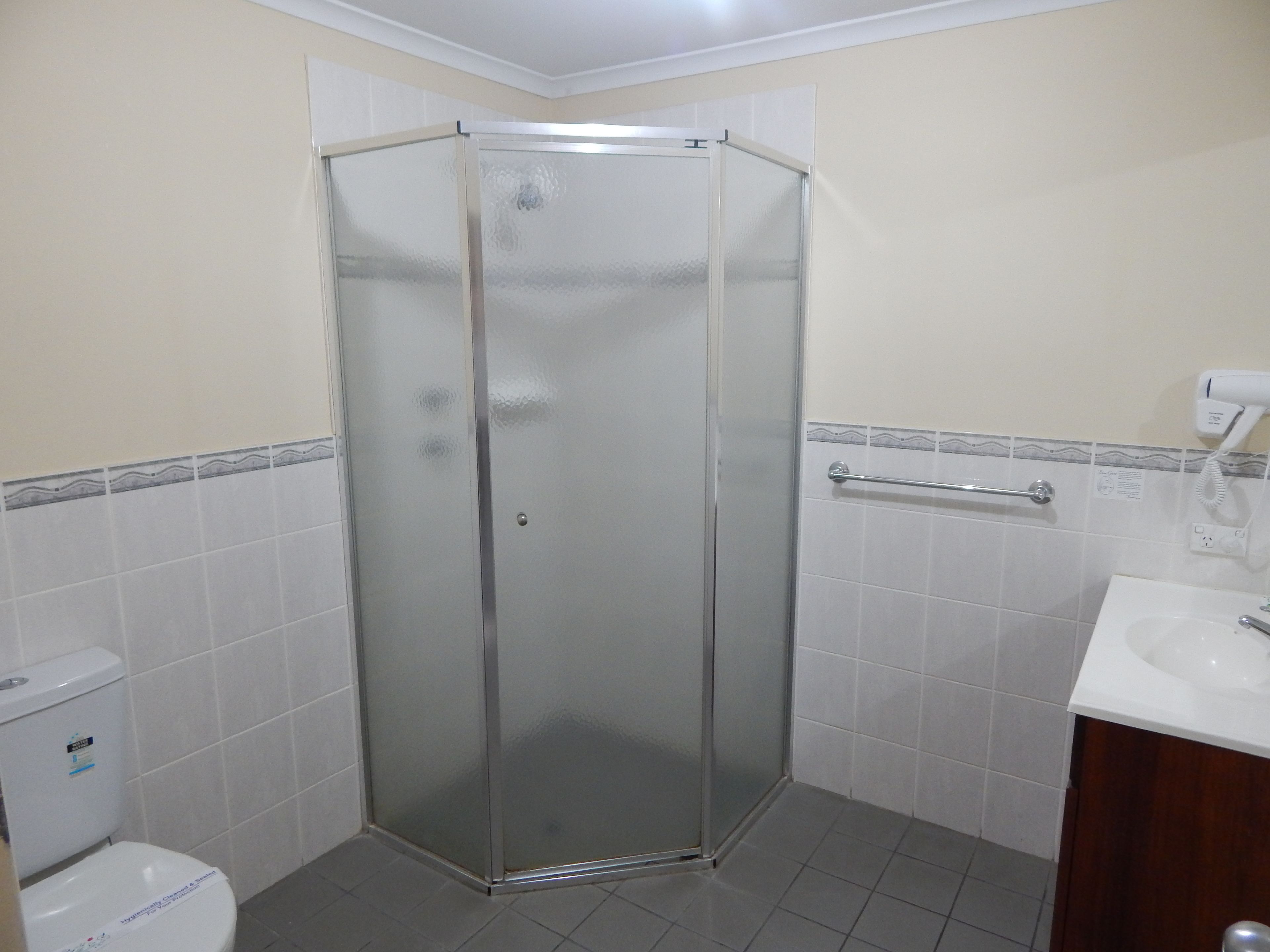 Un baño con cabina de ducha de vidrio, inodoro y lavabo con espejo.