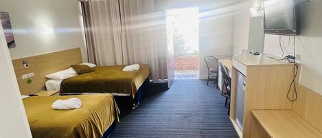 A hotel room with two beds, a desk, a chair, a television, and a window with curtains.