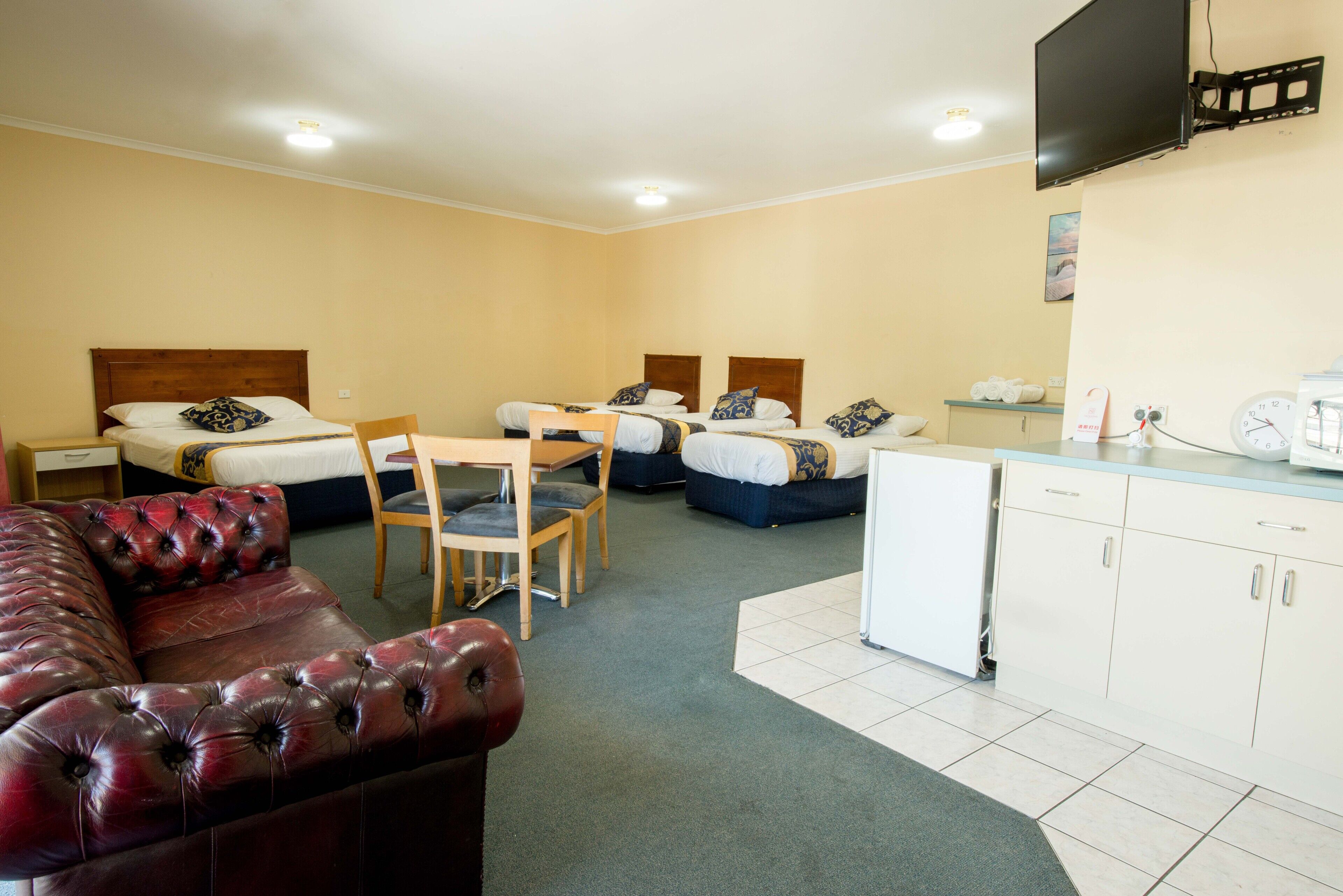 Habitación de hotel con sofá, dos camas, una mesa de comedor y zona de cocina.