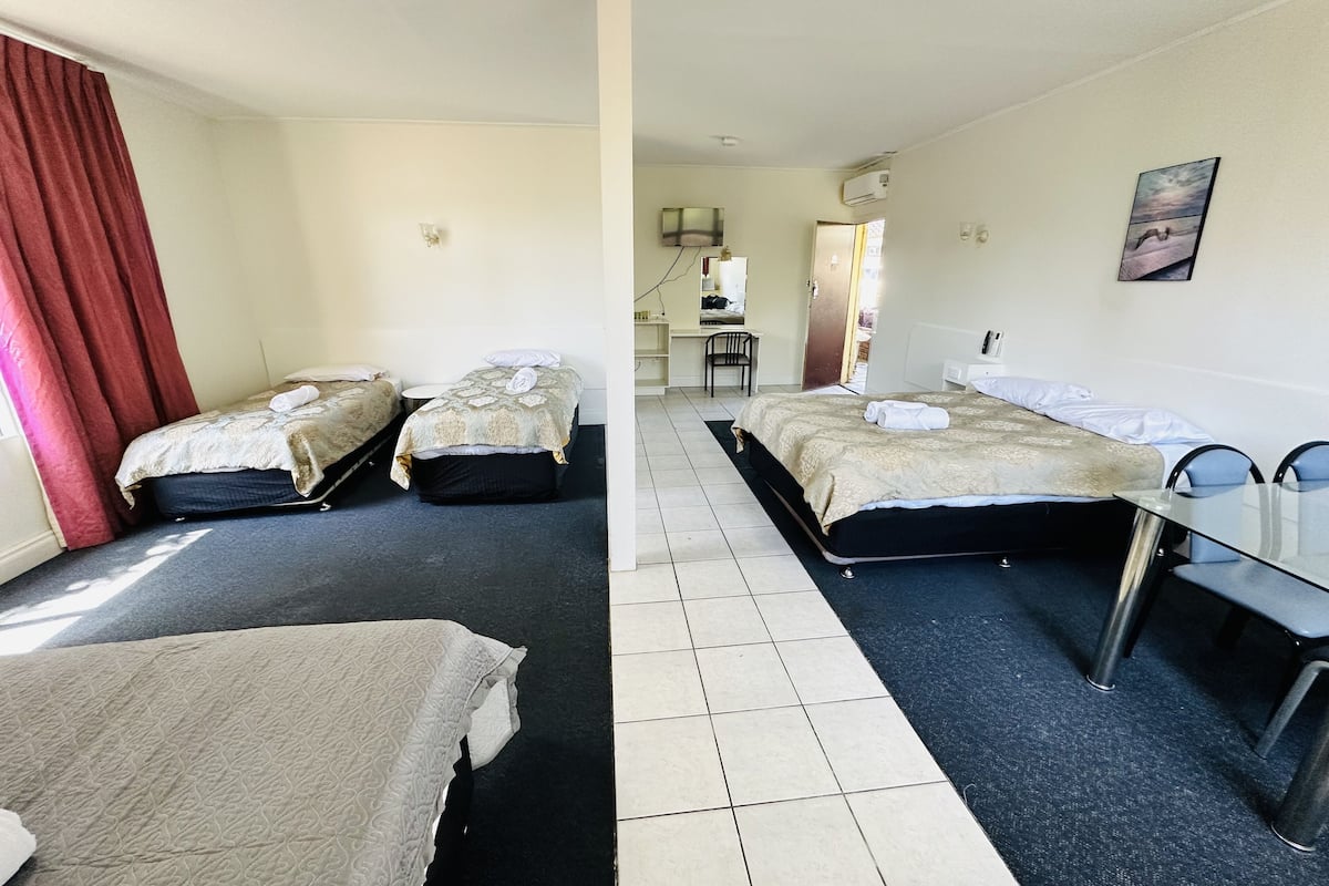 A hotel room with two beds, a desk, and a chair.