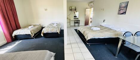 A hotel room with two beds, a desk, and a chair.