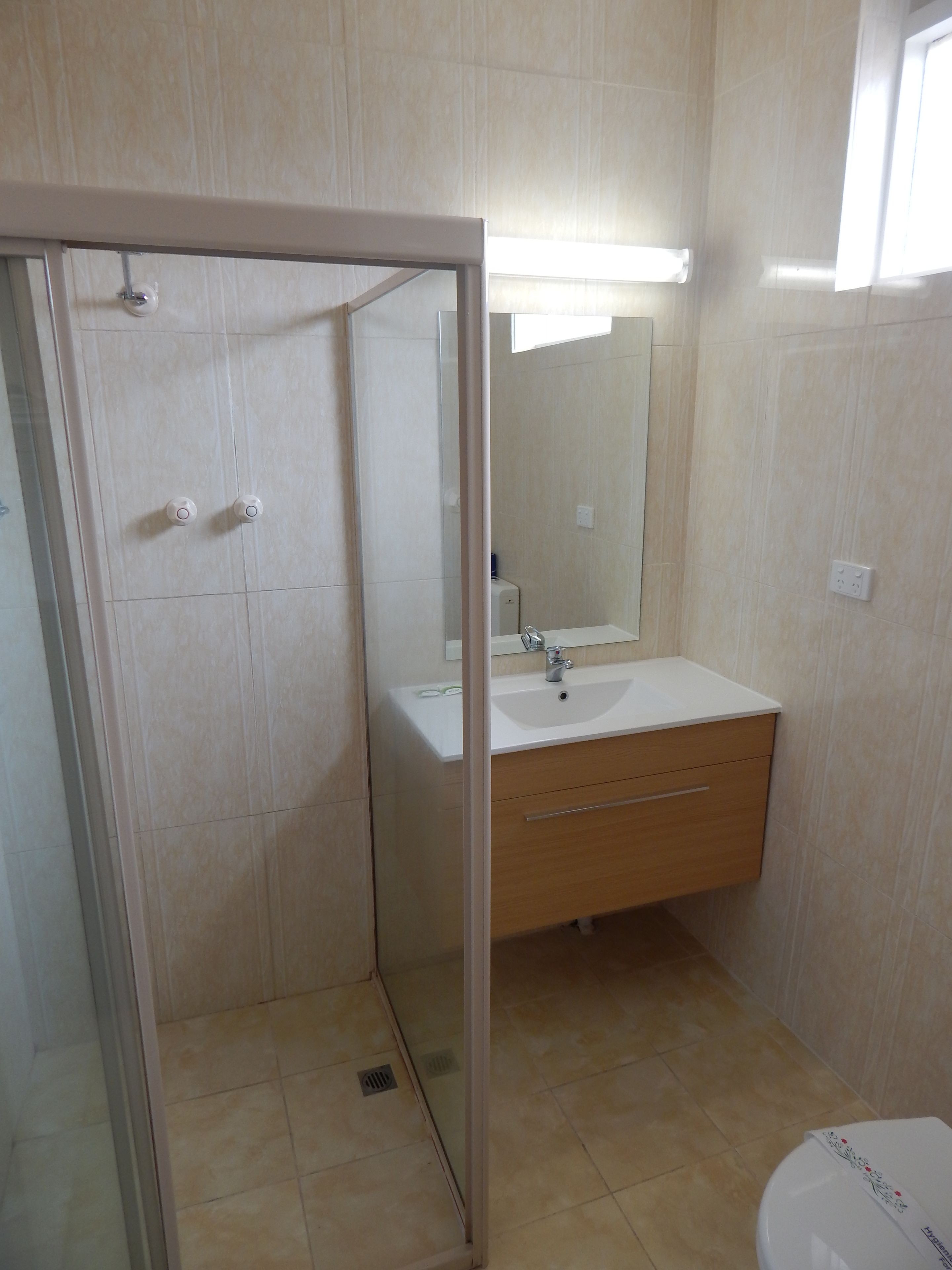 A bathroom with a glass-enclosed shower, a sink with a mirror, and a toilet.