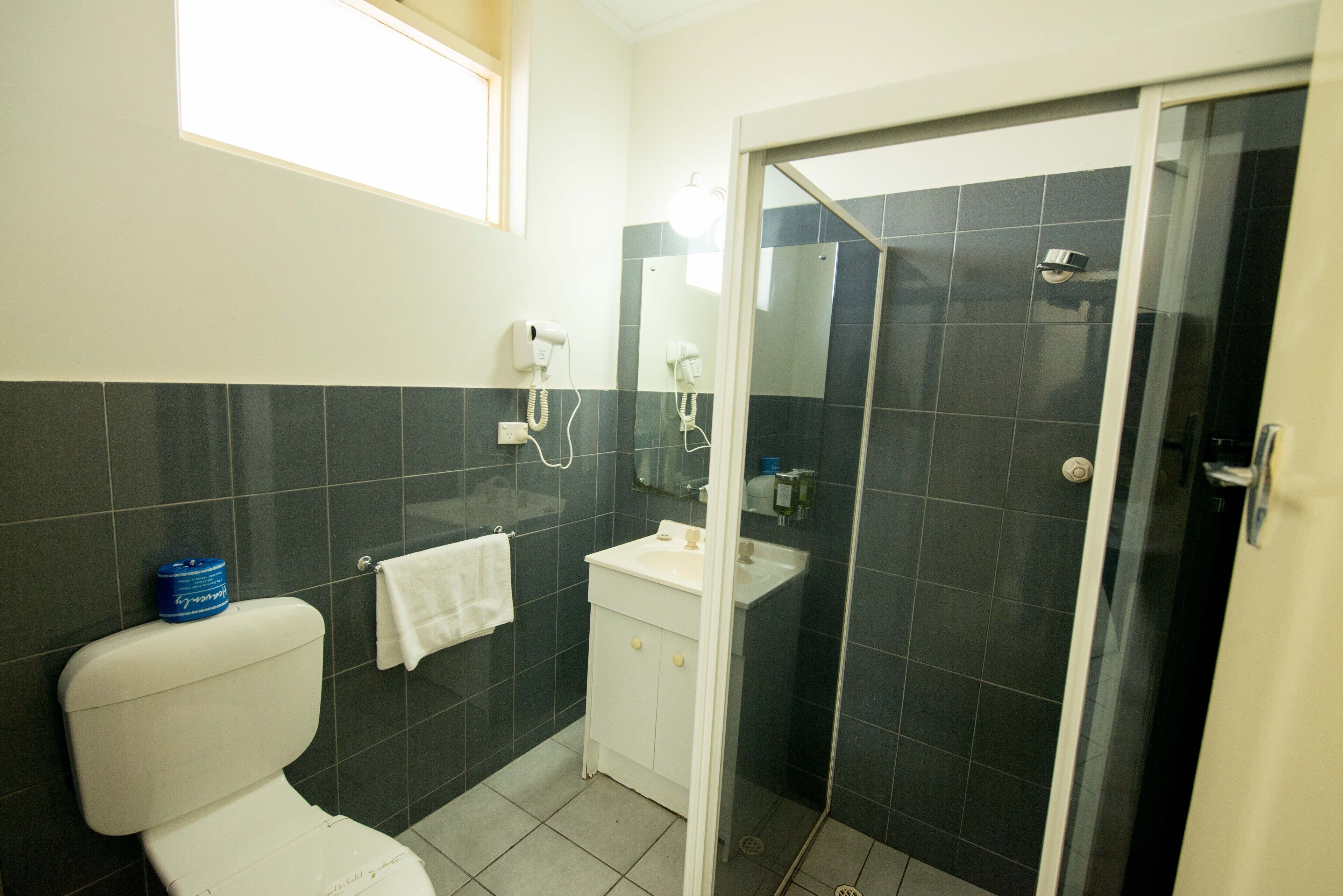 A bathroom with a toilet, sink, and shower area.