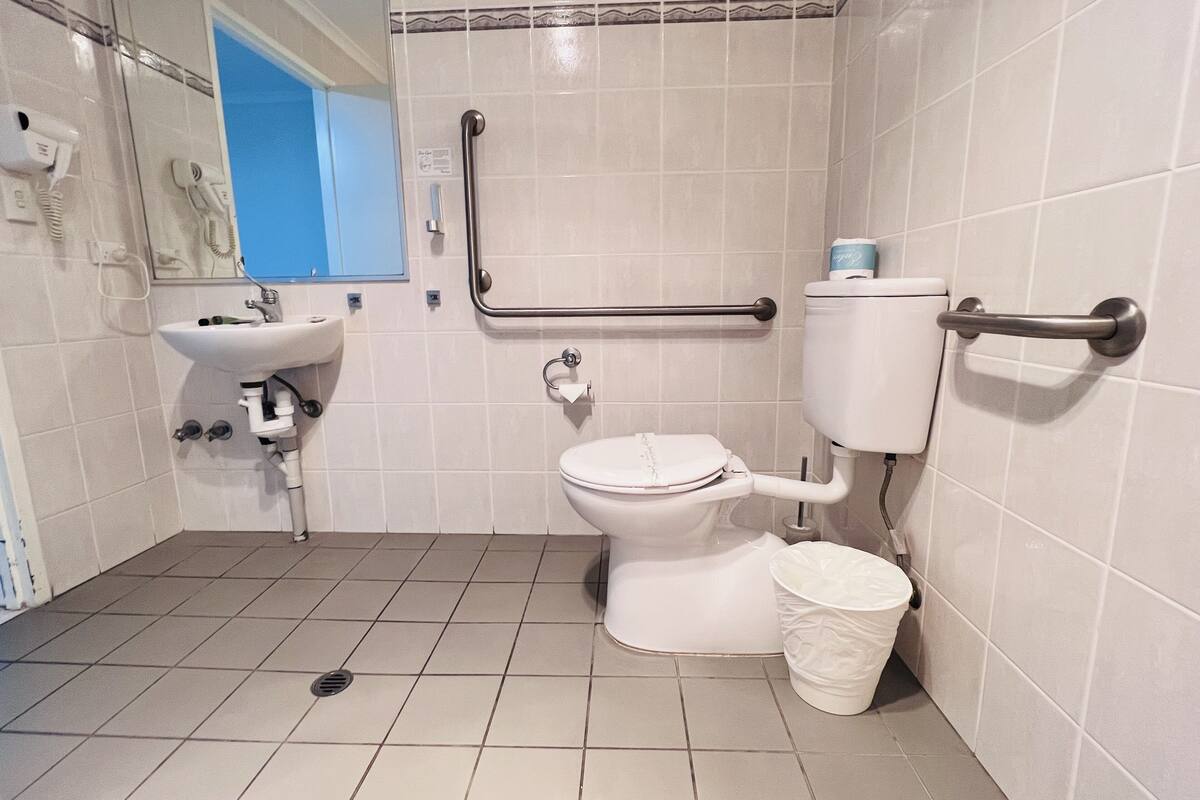 A bathroom with a toilet, sink, and hand dryer.