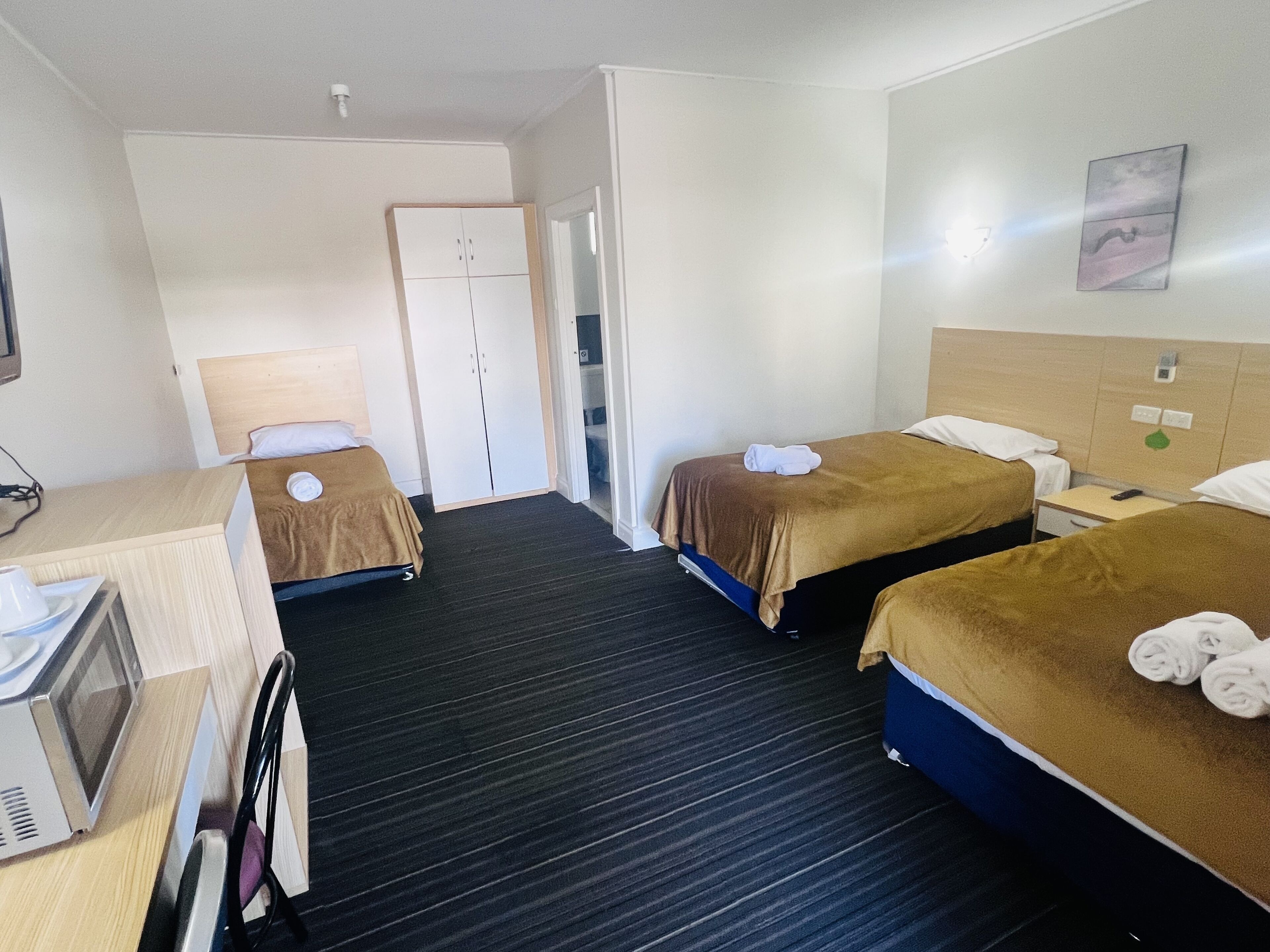 Habitación de hotel con dos camas, un escritorio, un microondas y un armario.