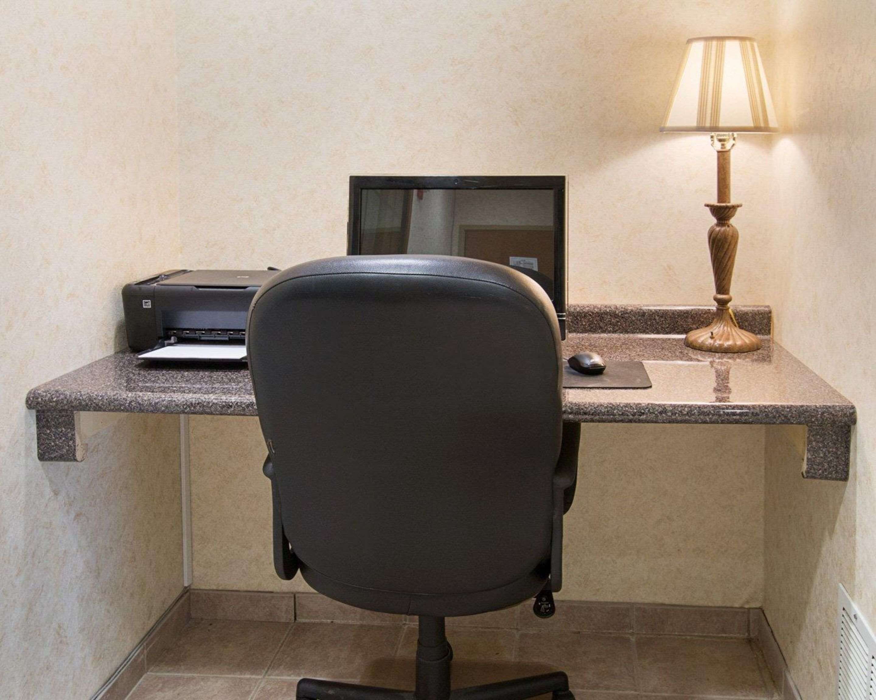 Un espace de travail comprenant un bureau, un ordinateur, une imprimante, une chaise et une lampe.
