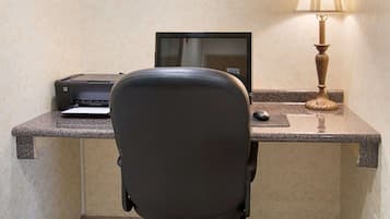 Un espace de travail comprenant un bureau, un ordinateur, une imprimante, une chaise et une lampe.