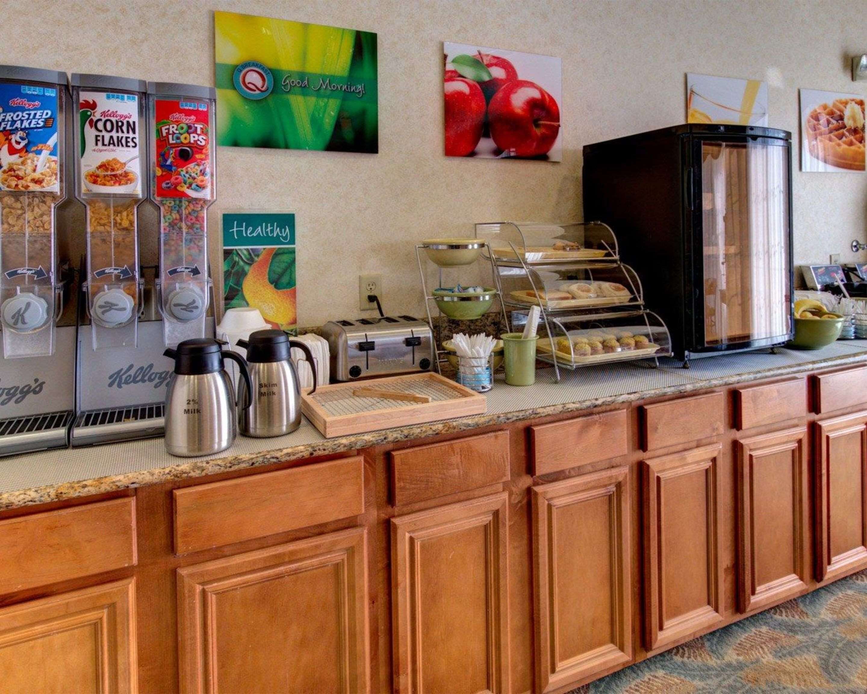 A breakfast bar with various food items, a coffee maker, a toaster, and a refrigerator.