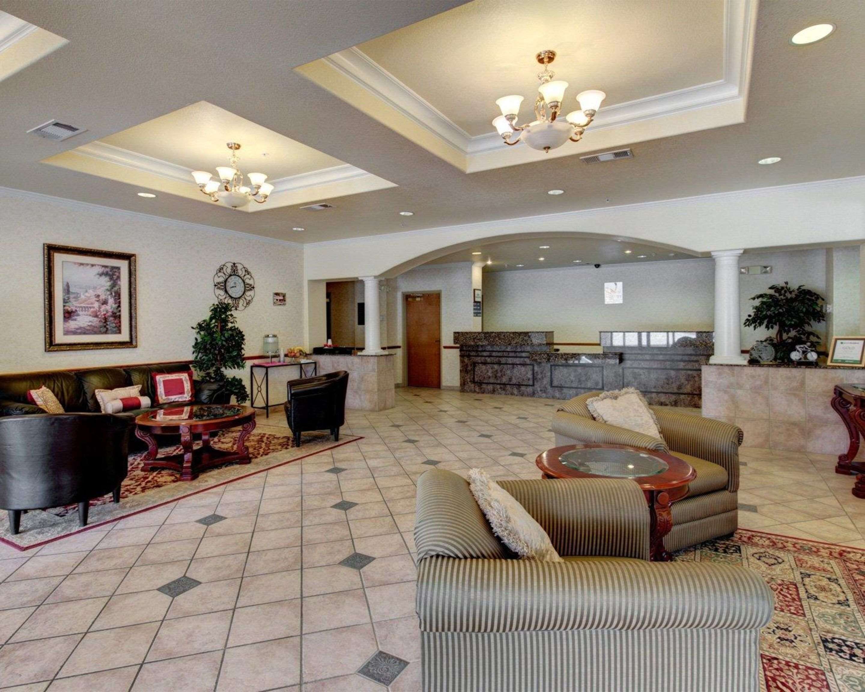 A spacious lobby with a reception desk, seating area, and decorative elements like a chandelier and artwork.