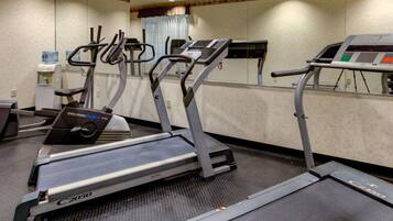 Een fitnessruimte met loopbanden, een waterfontein en een spiegelwand.
