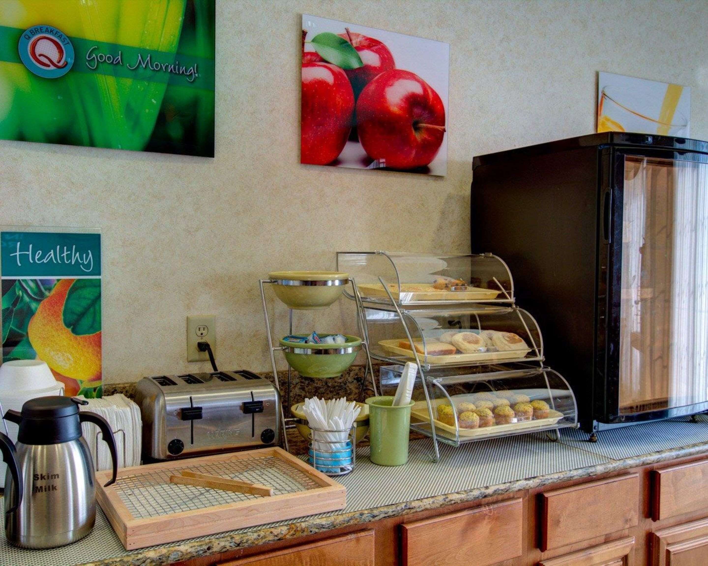 Una estación para el desayuno con una tostadora, una cafetera y un expositor con muffins.
