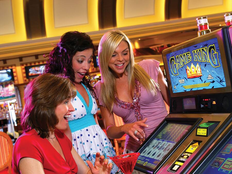 A group of people interacting with a slot machine in a brightly lit indoor setting.