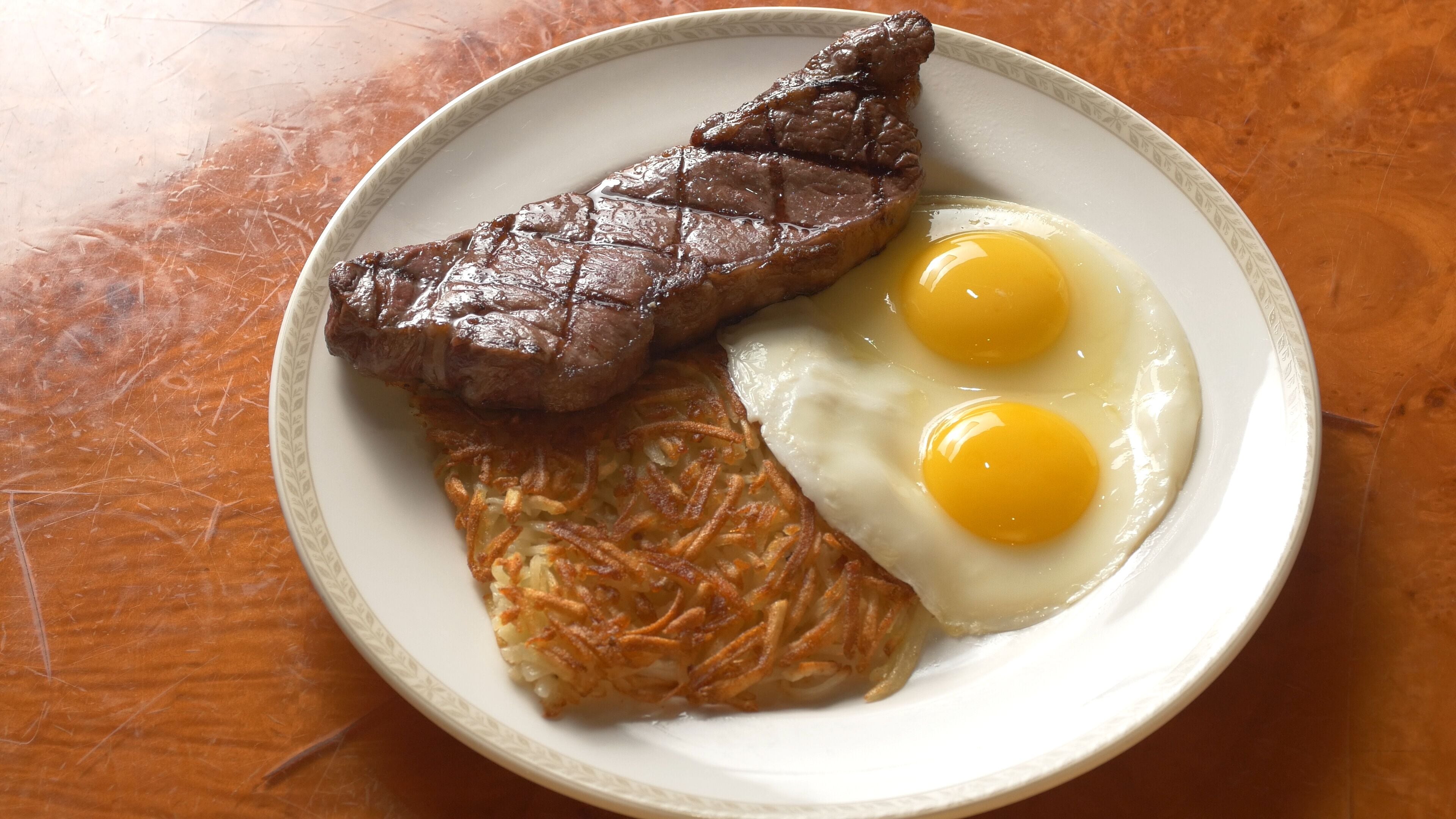 A plate with a steak, two fried eggs, and a hash brown.
