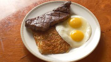 A plate with a steak, two fried eggs, and a hash brown.