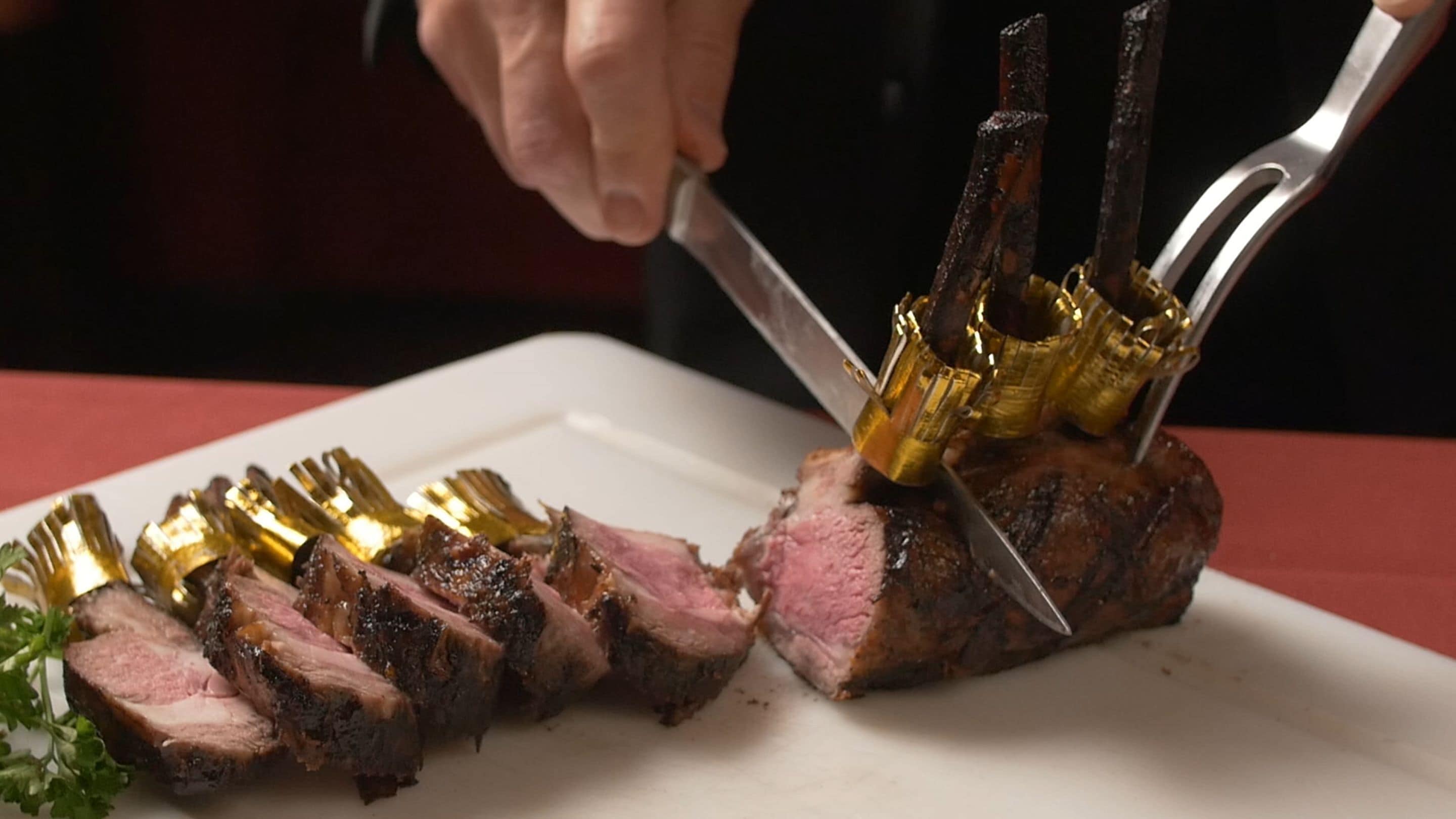 A person slicing a cooked meat dish with a knife and fork.