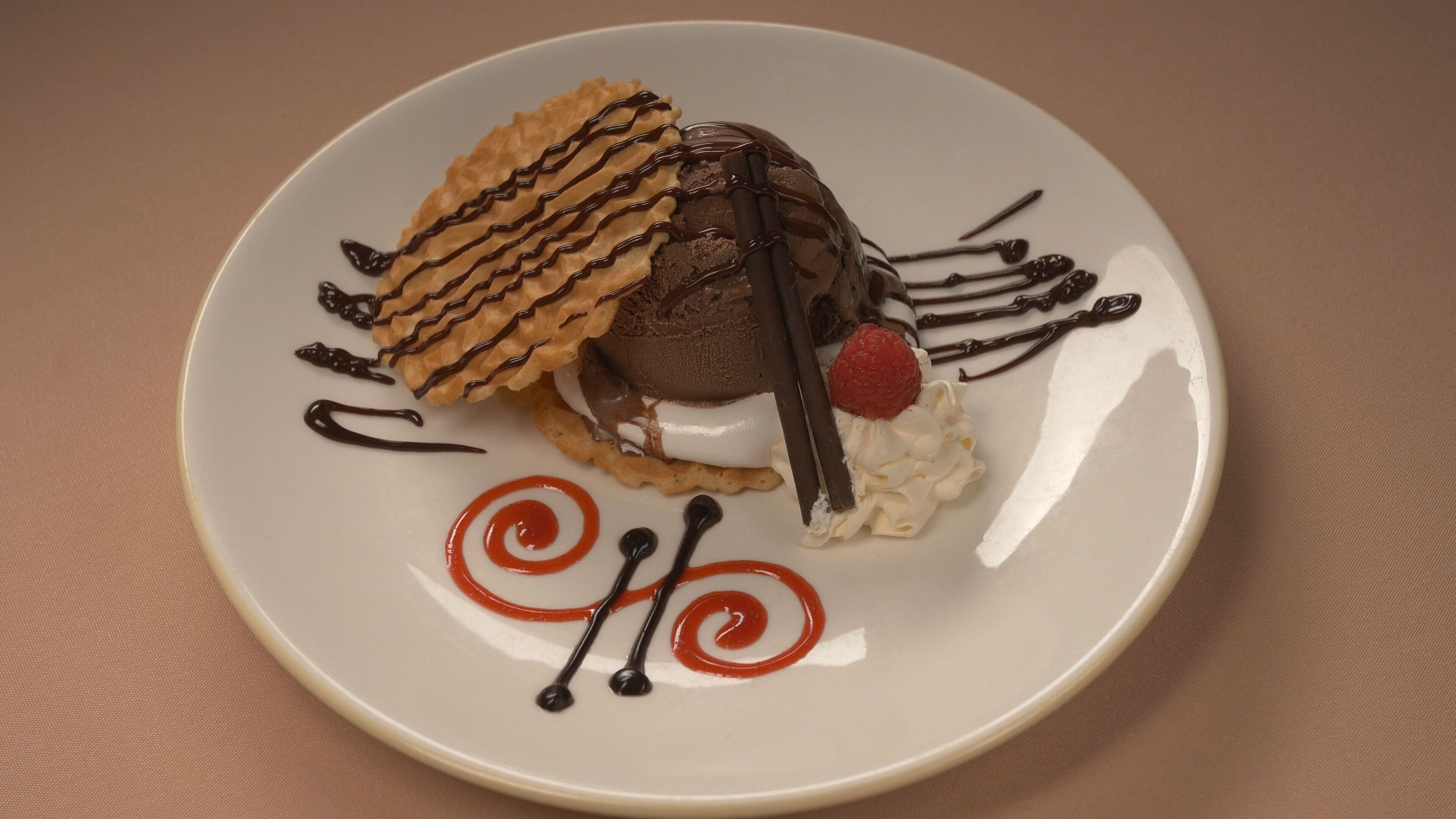 A dessert on a plate with chocolate, whipped cream, and a strawberry.