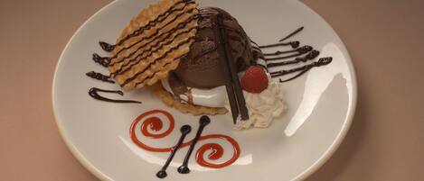A dessert on a plate with chocolate, whipped cream, and a strawberry.