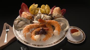 A seafood platter with shrimp, oysters, and lemon slices on a plate.