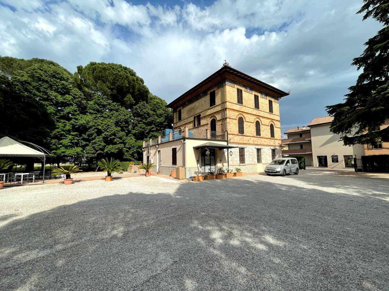 Un edificio con facciata in pietra, un balcone e un'auto parcheggiata di fronte.