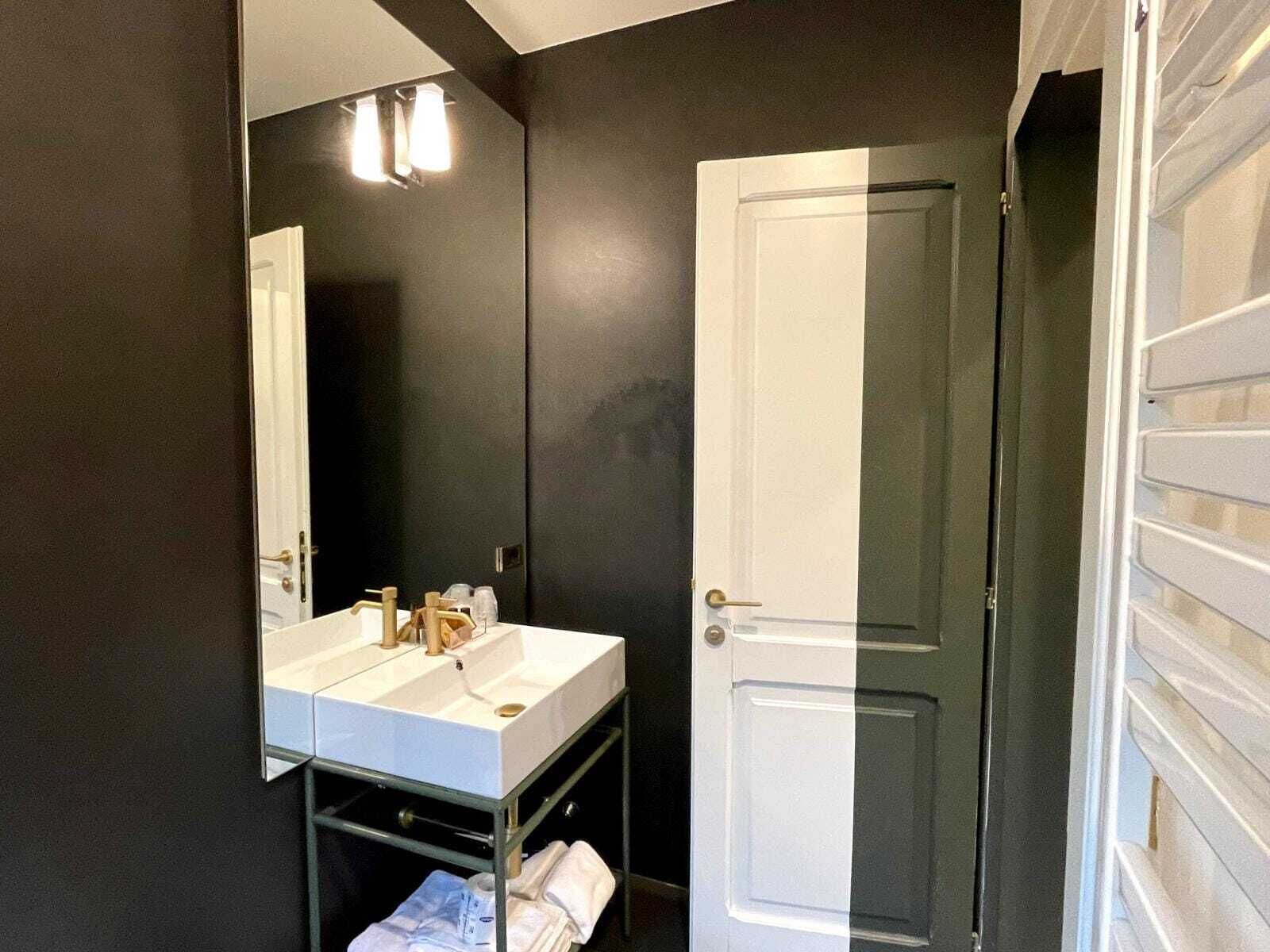 Une salle de bain avec un lavabo blanc, un miroir et une porte.