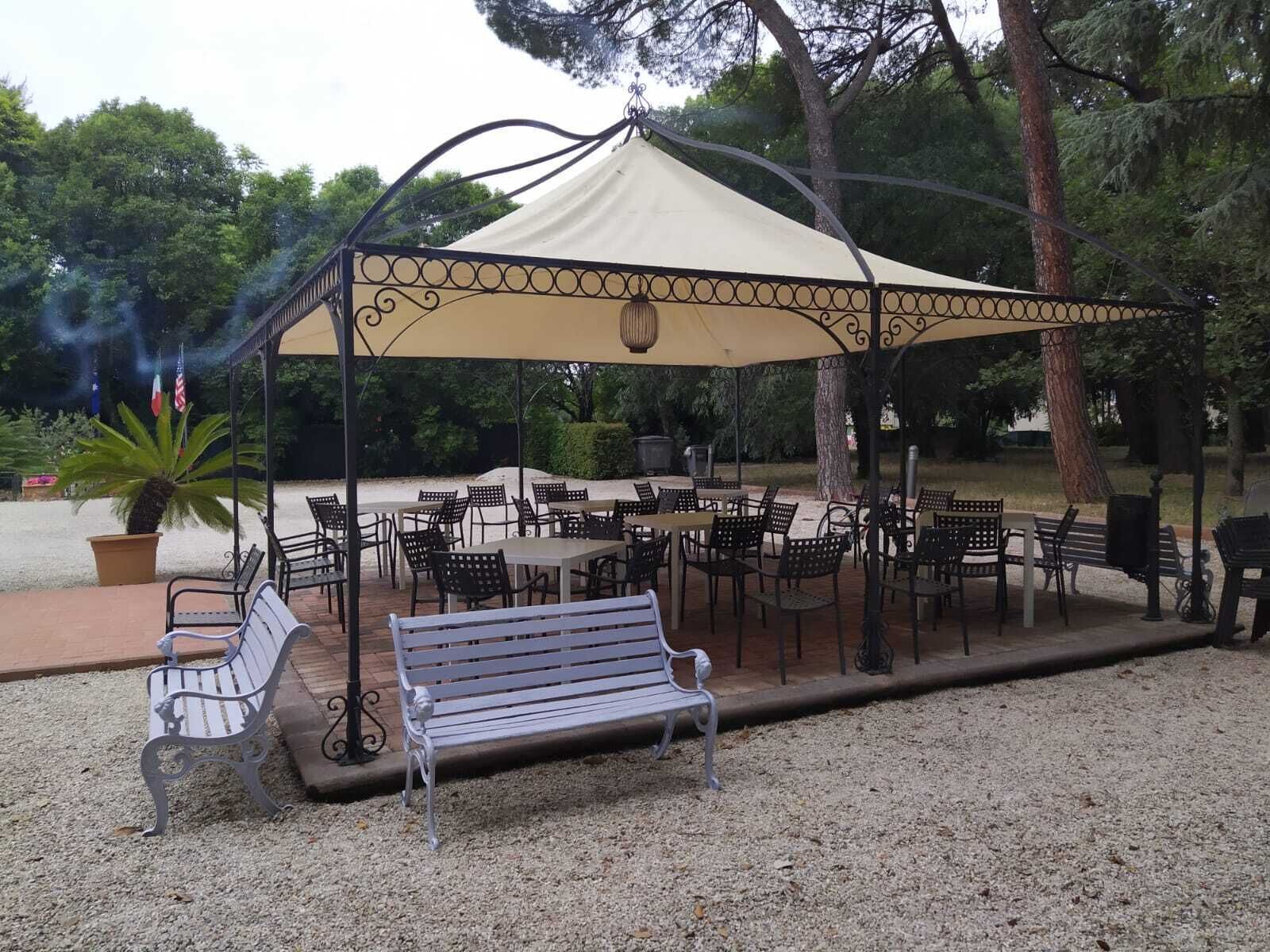 An outdoor patio area with tables and chairs under a canopy.