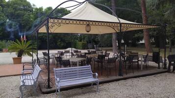 An outdoor patio area with tables and chairs under a canopy.