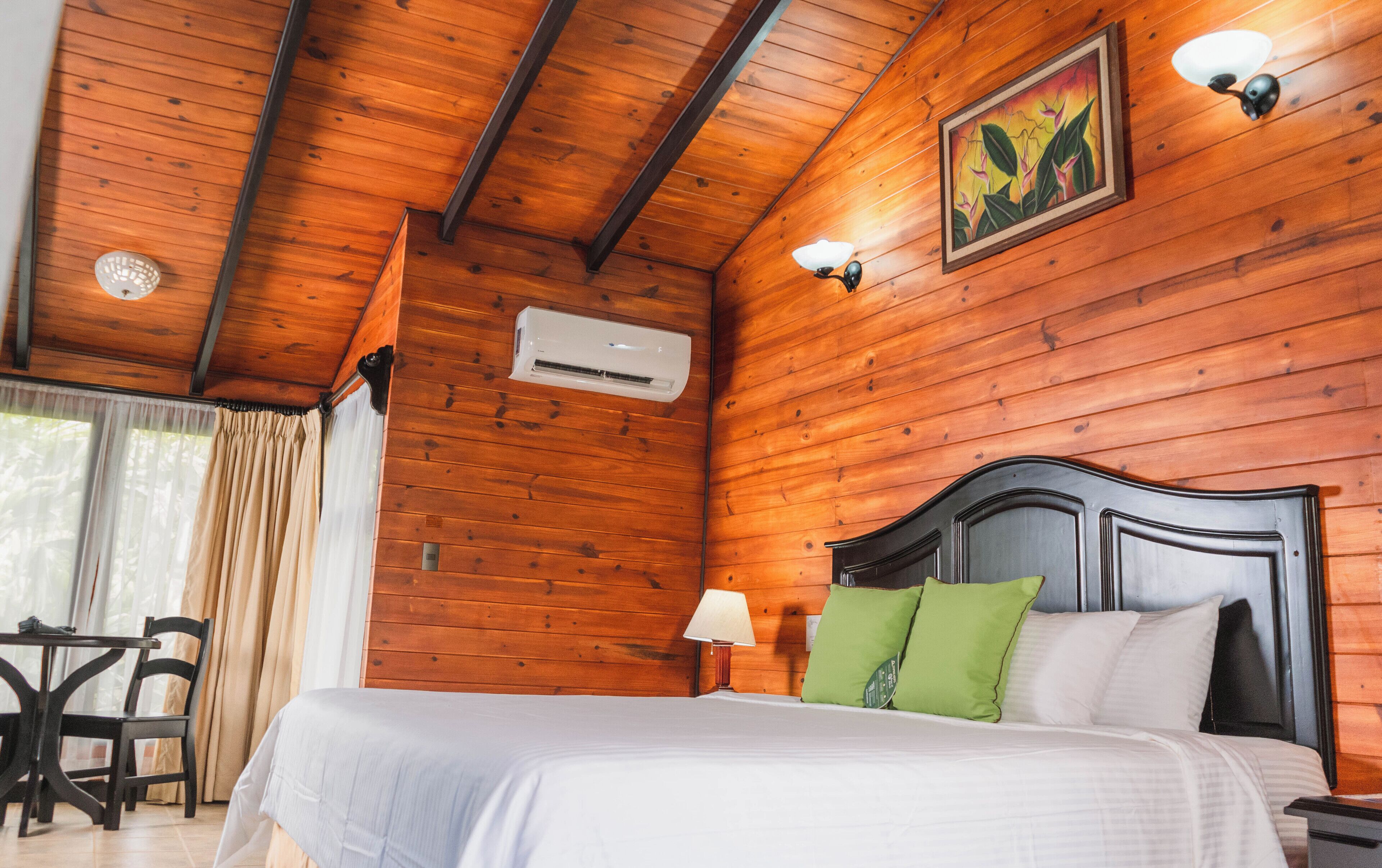 Habitación con paneles de madera, una cama, una mesa y una silla.