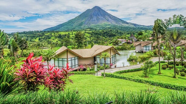 Un complexe hôtelier offrant une vue sur les montagnes, un étang et une végétation luxuriante.