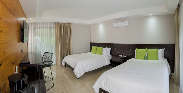 A hotel room with two beds, a desk with a chair, a TV mounted on the wall, and an air conditioning unit. - Montaña de fuego Mountain Resort & Spa (La Fortuna)