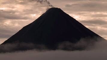 Una montaña con un pico que emite humo, rodeada de nubes.