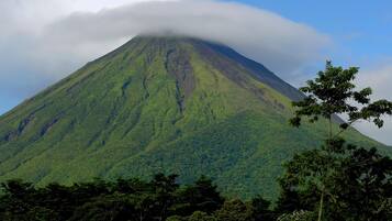 A mountain with a dense forest at its base and a cloud partially covering its peak.
