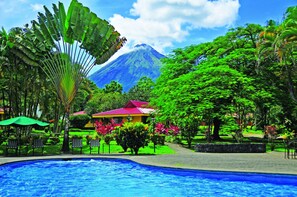 A pool area with a view of a volcano in the background. - Arenal Country Inn (La Fortuna)