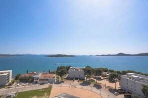 A coastal building complex with a parking area, a road, and a view of the sea. - Hotel Punta (Vodice)