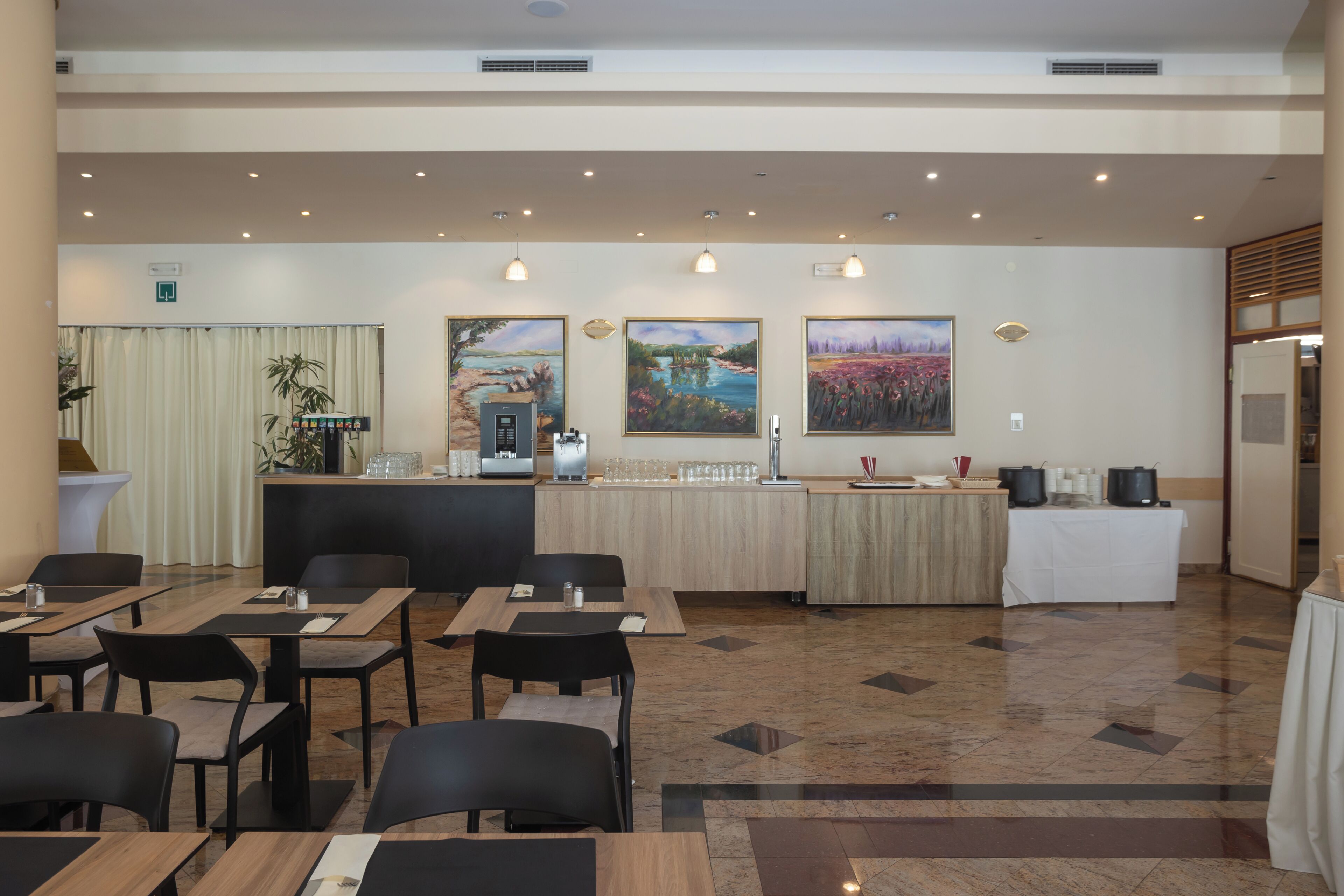 Un hall d’hôtel avec des tables, des chaises, des œuvres d’art, un comptoir de réception et un espace dédié au café.